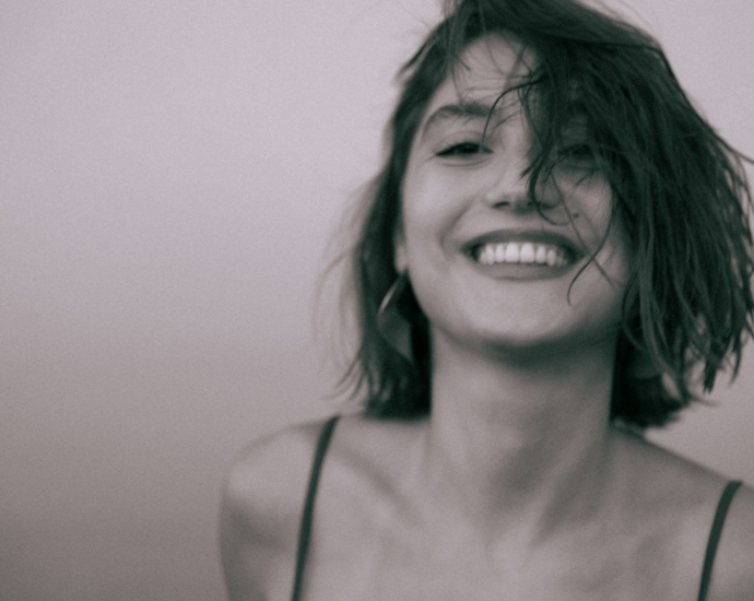 A woman with wet hair smiling and holding a cell phone