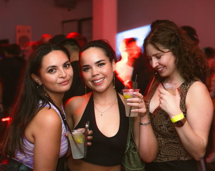 a group of women standing next to each other holding drinks