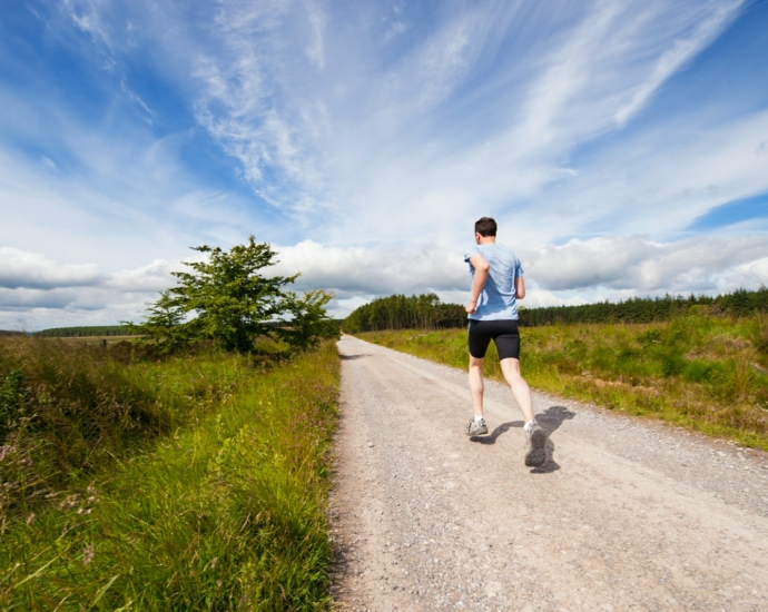 man running on road near grass field