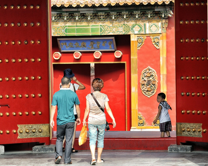 three people walking toward red building