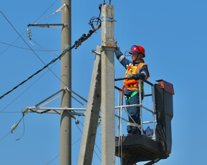 a man standing on top of a metal pole next to power lines