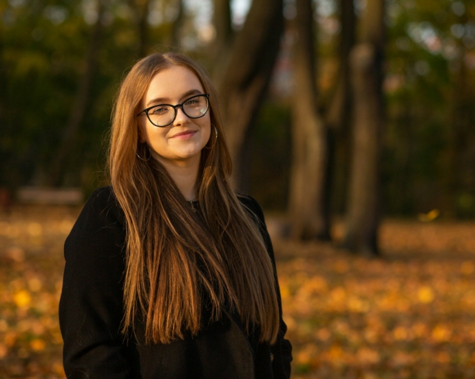 a woman wearing glasses standing in a park