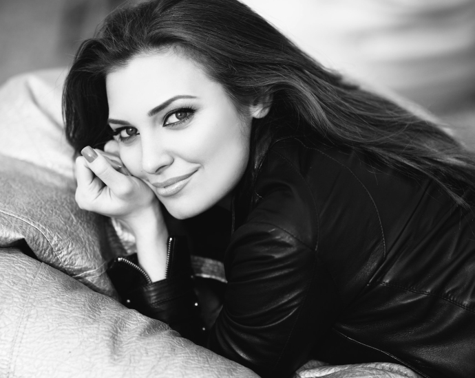 A black and white photo of a woman laying on a couch