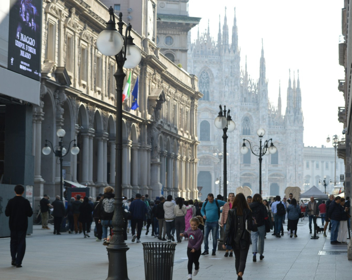 A crowd of people walking down a street next to tall buildings