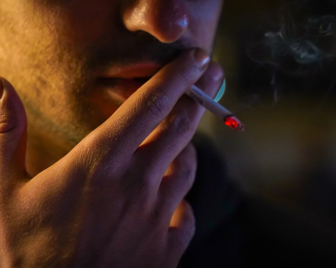 a man smoking a cigarette in the dark