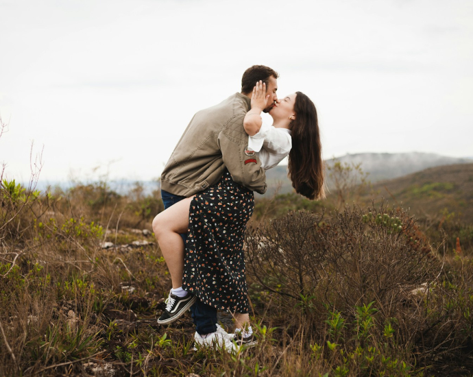 a man and a woman kissing in a field