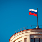 Russian national flag waving on a building in St. Petersburg under clear skies.