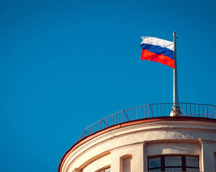 Russian national flag waving on a building in St. Petersburg under clear skies.