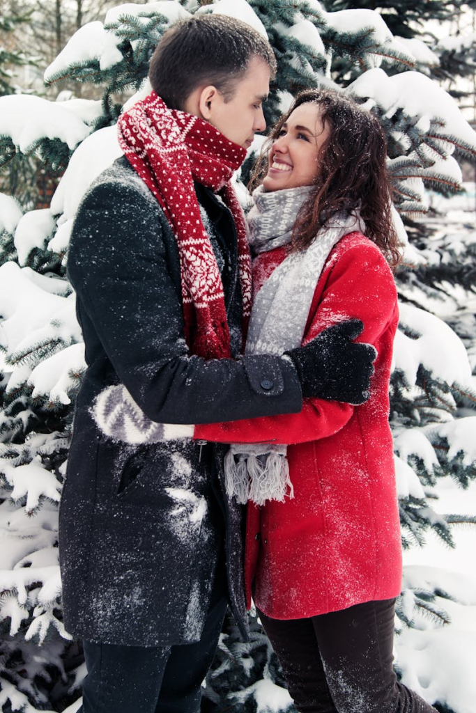 Couple enjoying a loving embrace in a snowy forest, exuding warmth and happiness.