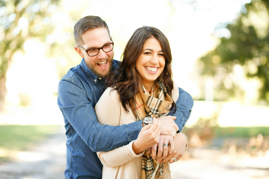 A happy couple enjoying an outdoor engagement photoshoot with laughter and love.