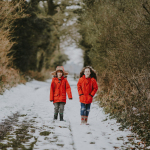 two children walking near bushes during winter