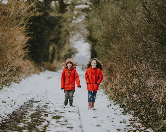 two children walking near bushes during winter