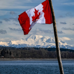 a canadian flag flying over a body of water