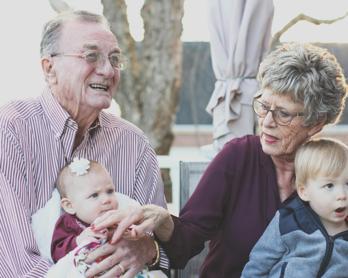 Grandparents spending joyful moments with their grandchildren in an outdoor setting, captured candidly.