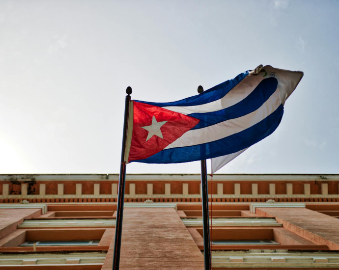 Cuban flag waving against a historic building in Havana, capturing national pride and architectural beauty.