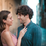 A happy young couple embracing and smiling while enjoying a romantic moment outdoors.