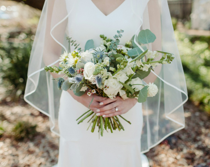 woman in white wedding dress holding white flower bouquet