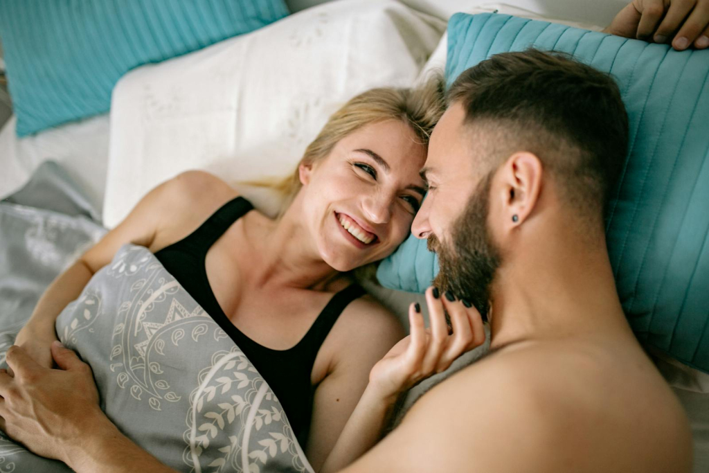 A cheerful couple cuddling in bed, showcasing love and intimacy in a home setting.