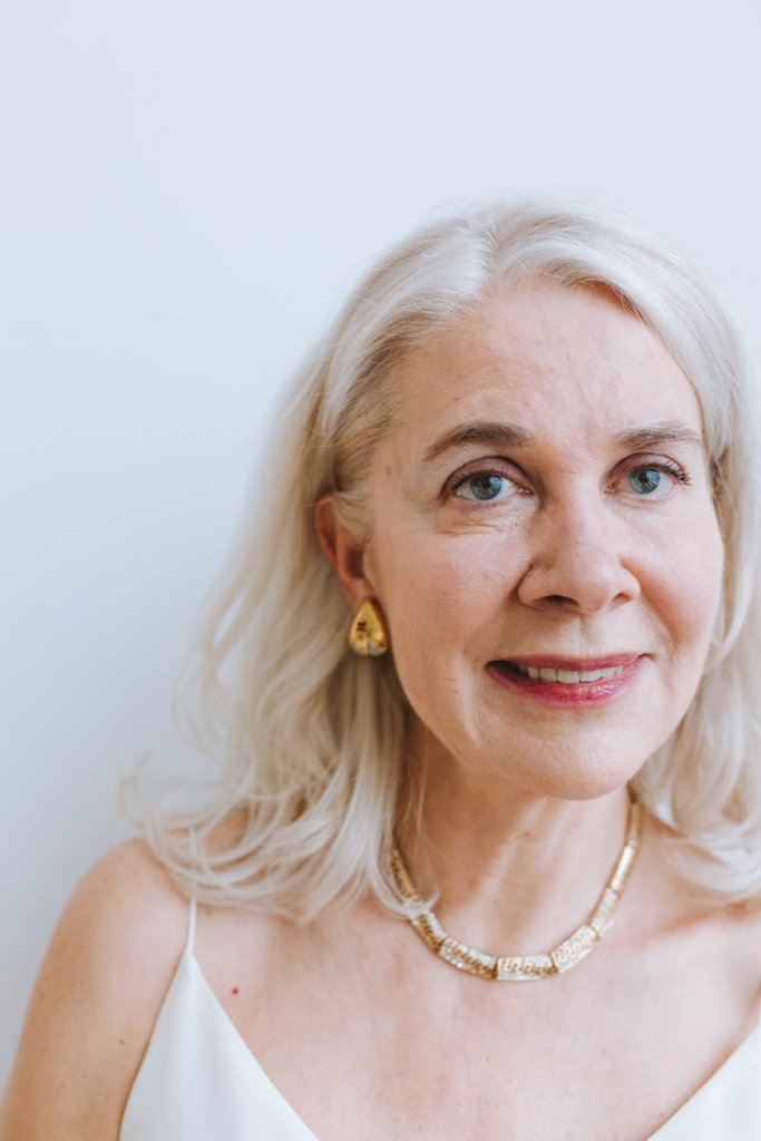 A smiling senior woman with earrings and necklace from a portrait session.