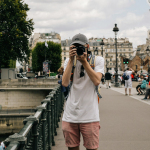 man holding DSLR camera beside bridge