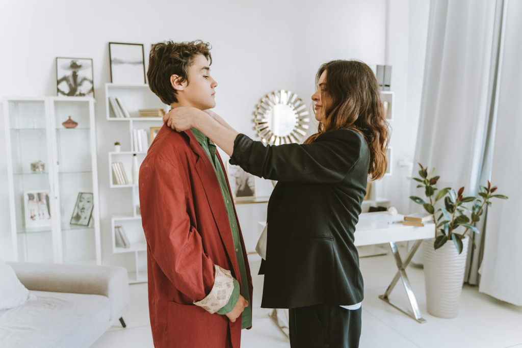 Woman adjusting her son's red coat inside a modern and elegantly decorated office space.