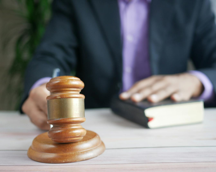 A wooden gavel and legal book represent justice in a court setting, emphasizing order and legal authority.