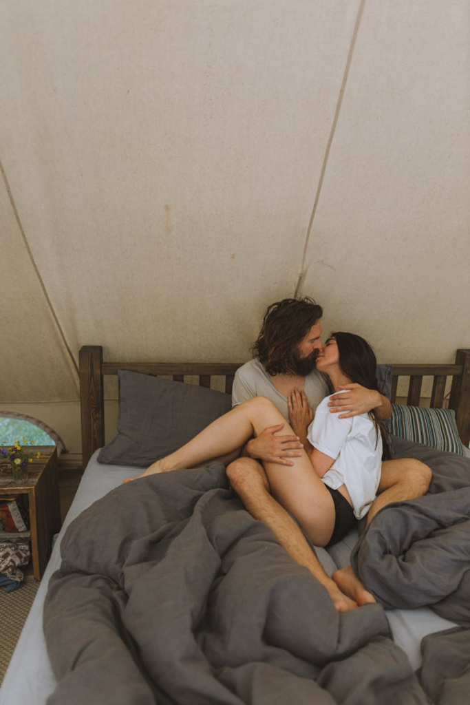 Intimate scene of a couple embracing on a bed, creating a cozy and romantic atmosphere indoors.