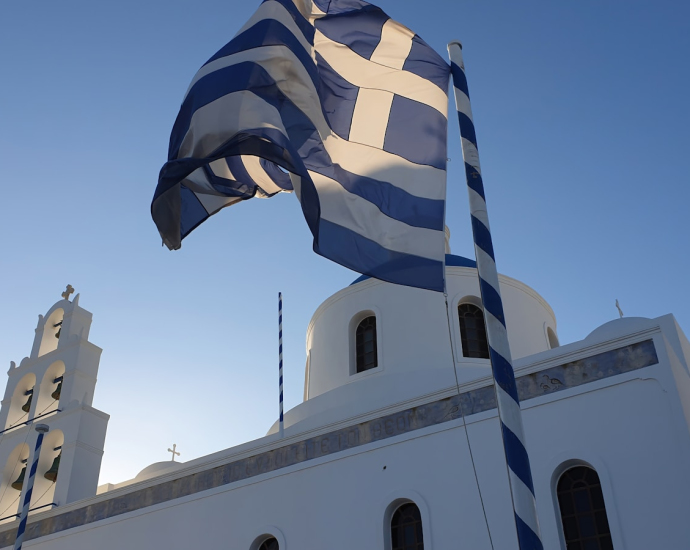 a large greek flag flying in front of a church