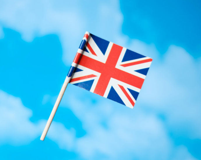 a small british flag flying in the blue sky