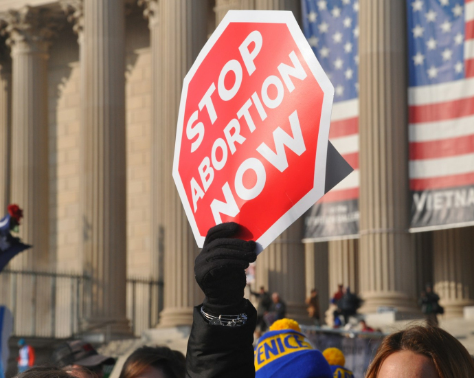 person holding red Stop Abortion Now signage