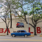 red sedan on road near trees during daytime