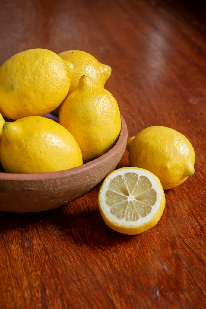 yellow lemon fruit on brown wooden bowl