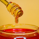 clear glass bottle pouring red liquid on clear drinking glass