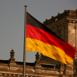 two flags flying next to each other in front of a building