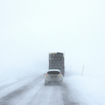 white car behind a truck on snowy road