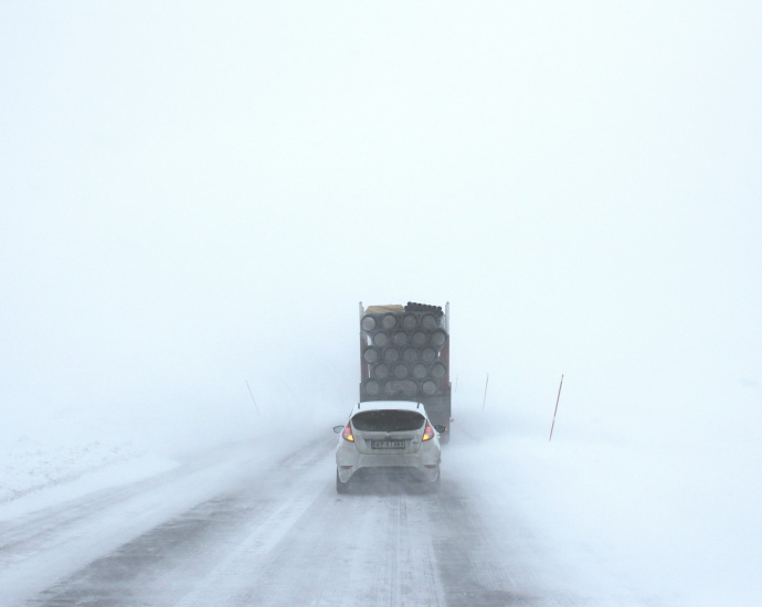 white car behind a truck on snowy road