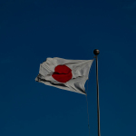 A flag flying in the wind with a blue sky in the background