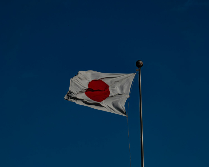 A flag flying in the wind with a blue sky in the background