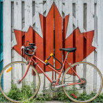 red road bike beside red and white wooden maple leaf painted wall