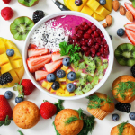 Vibrant smoothie bowl topped with assorted fresh fruits and muffins, perfect for a healthy snack.