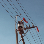 Engineer works on high power lines, ensuring electrical safety and maintenance.