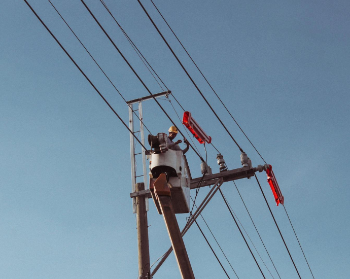 Engineer works on high power lines, ensuring electrical safety and maintenance.