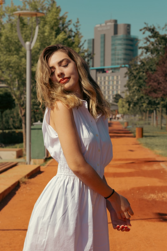 A woman in a white dress standing on a sidewalk