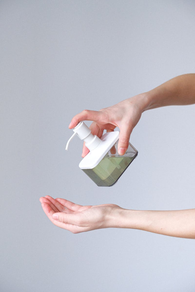 Close-up of a person applying liquid soap for hand hygiene. Indoors, bright lighting.