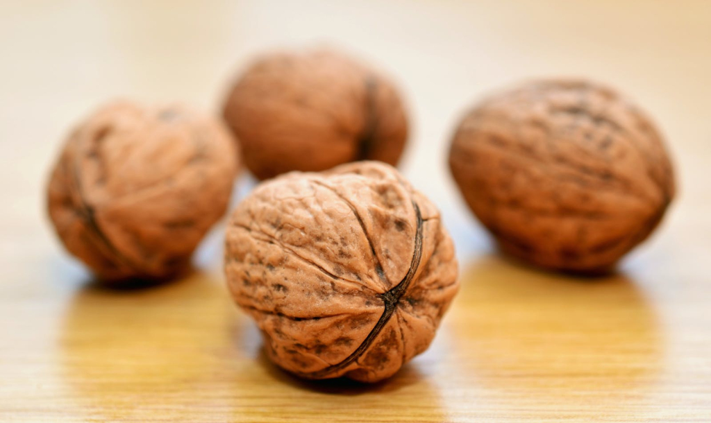 Macro shot of whole walnuts on a wooden surface, emphasizing texture.