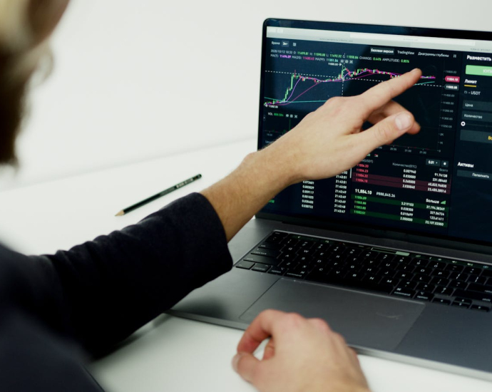 A person analyzing stock market graphs on a laptop screen, showcasing trading insights.