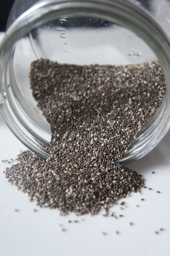 Chia seeds pouring out from a glass jar, perfect for healthy lifestyle or food blogs.