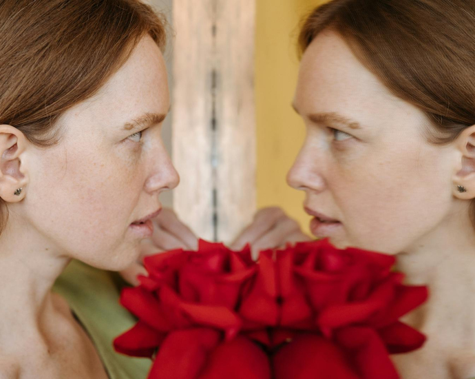 Close-up of a woman facing her reflection with red roses.