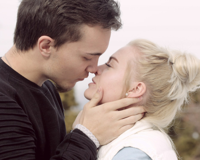 man wearing black top about to kiss woman