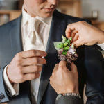 man in black suit holding bouquet of flowers